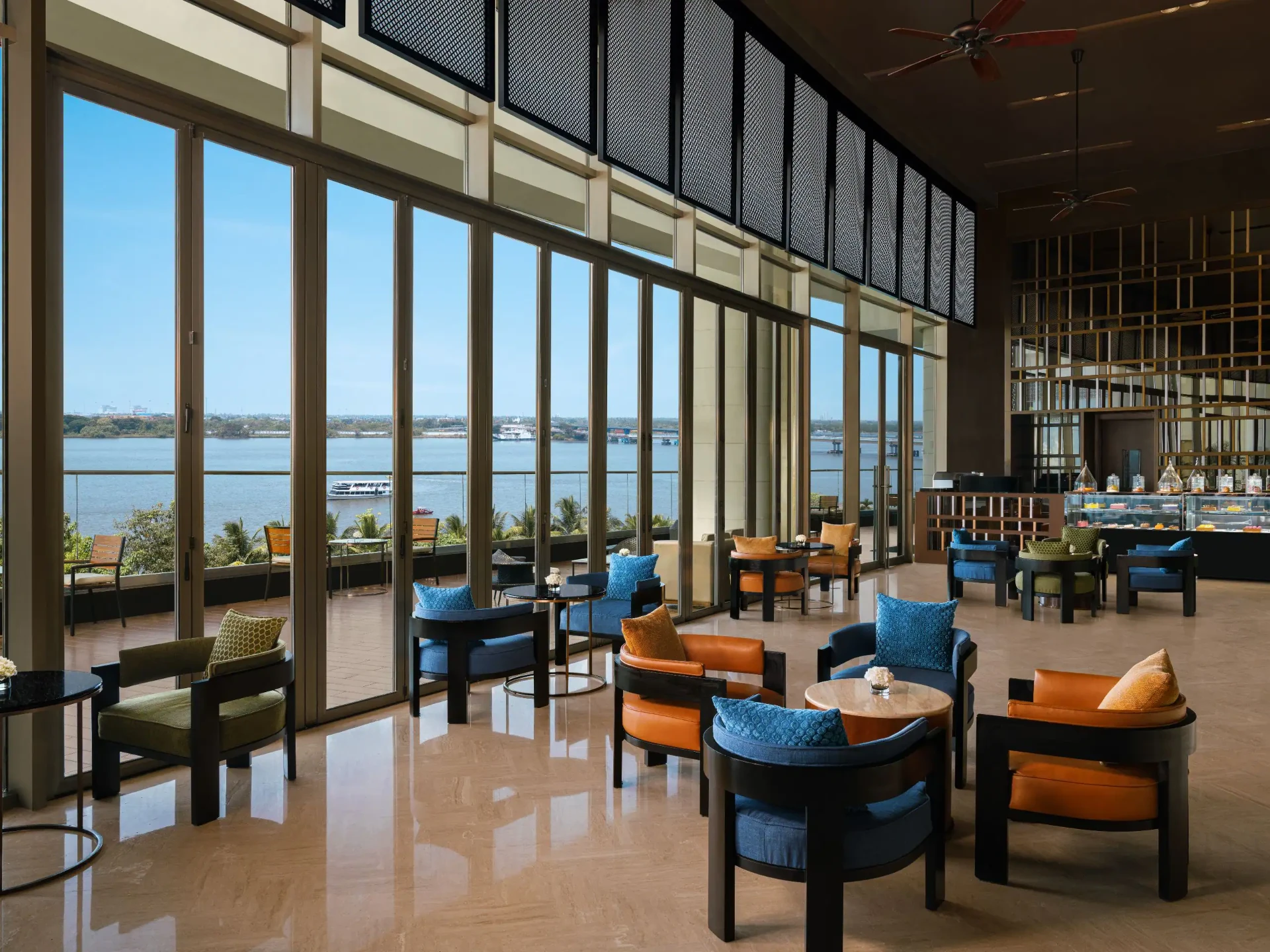 Hotel lounge with floor-to-ceiling windows overlooking the Kochi backwaters