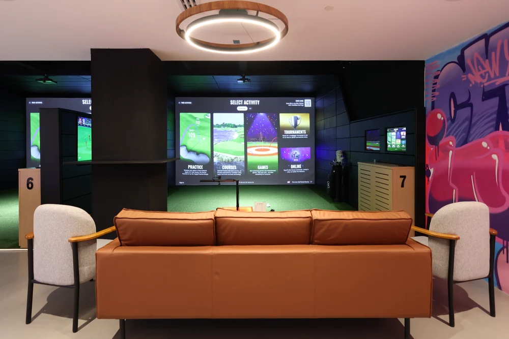 Indoor golf simulator bays and seating at Five Iron Golf Dubai
