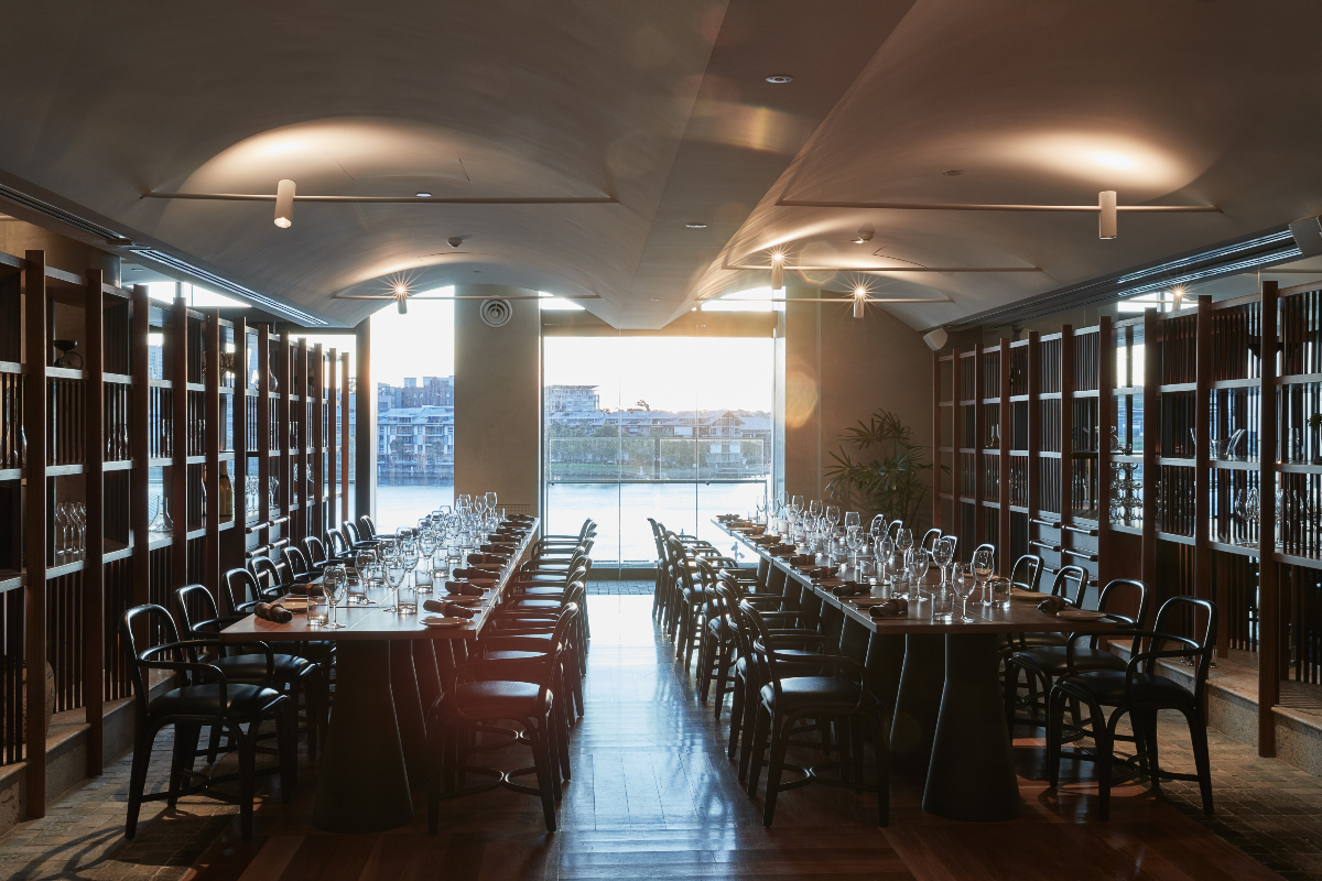 Long dining tables set in the Harbour Room overlooking the water